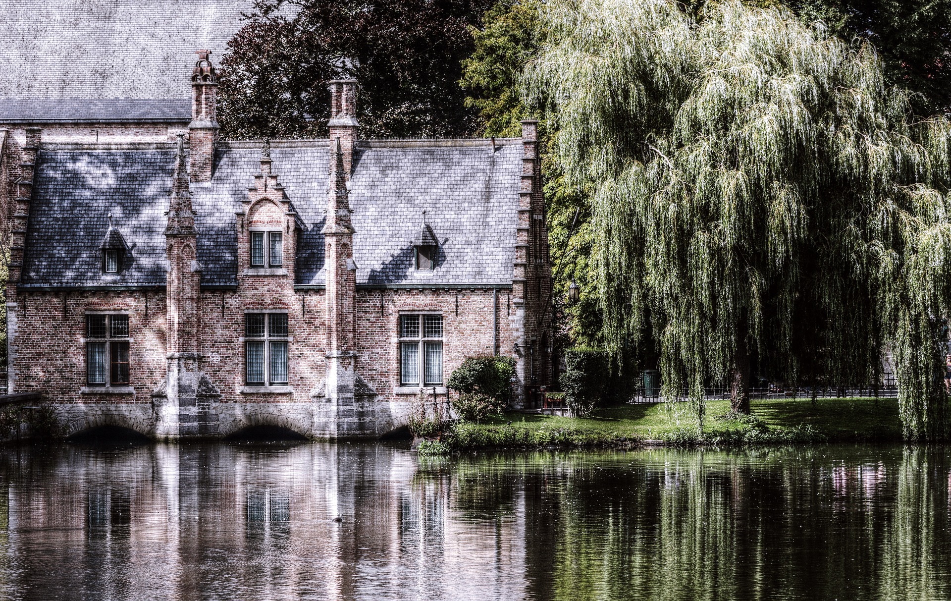 Manoir ancien au bord de l’eau, entouré de végétation